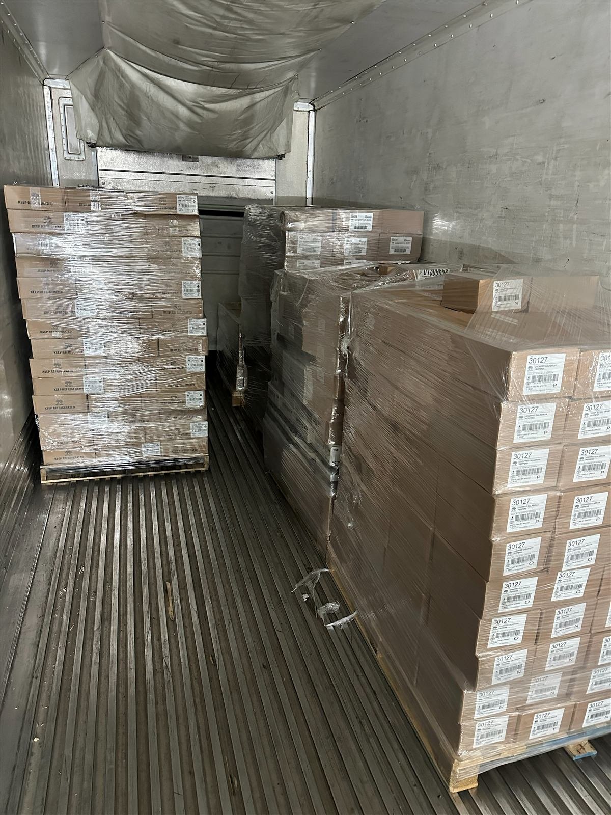 Restacked and shrink-wrapped pallets inside a trailer after pallet rework at NMV Expedition in Pineville, NC